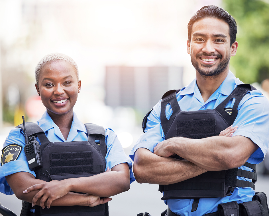 Two smiling police officers standing together.