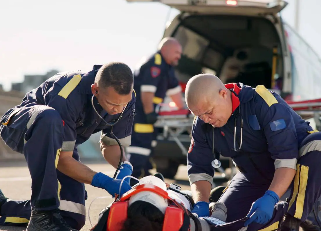 Emergency responders treating an injured person on the ground.