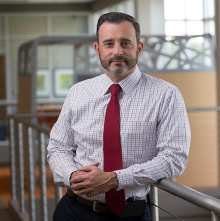 Confident professional man in office setting with red tie.