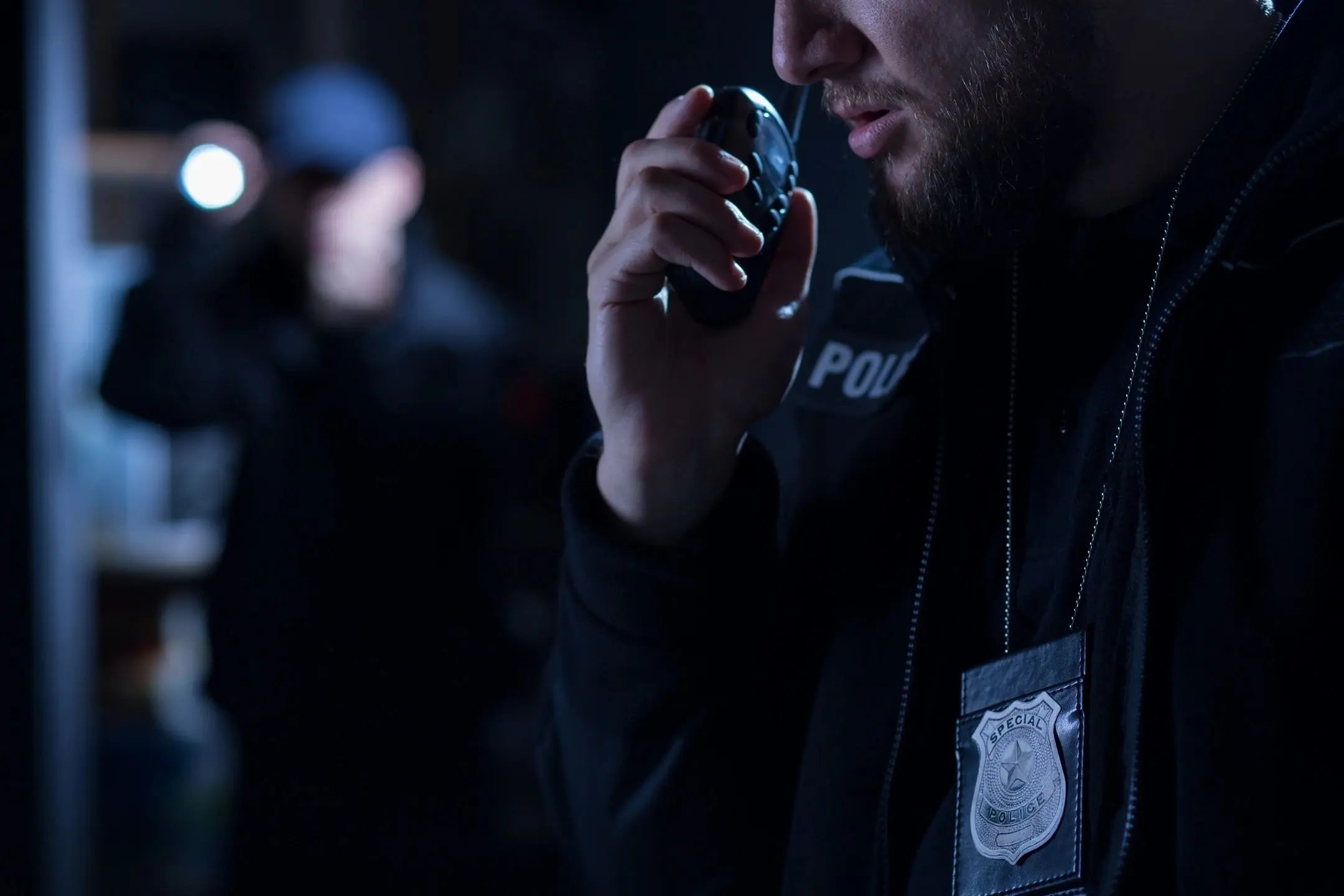Police officer speaking into a radio during night duty.